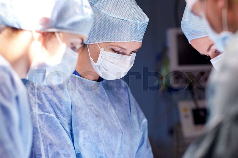 Surgery, medicine and people concept - group of surgeons at operation in operating room at hospital, stock photo