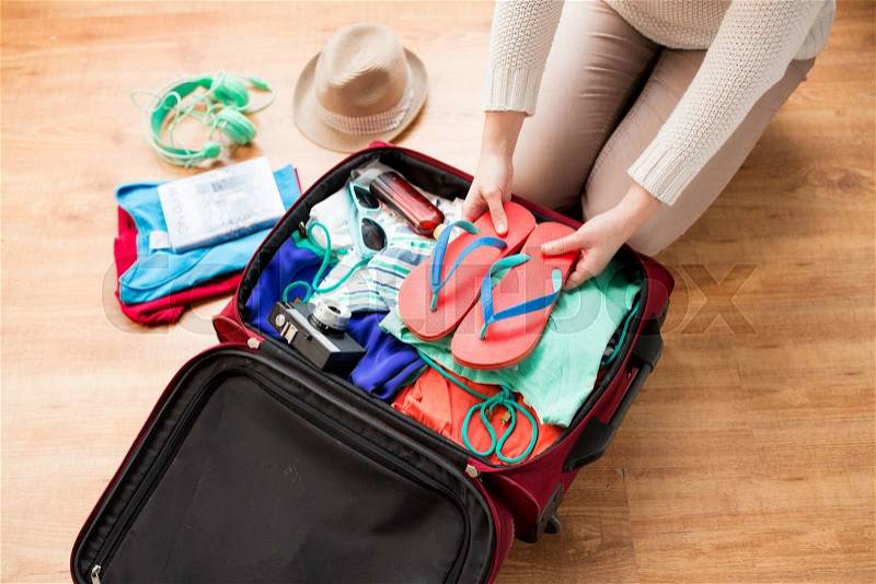 Summer vacation, travel, tourism and objects concept - close up of woman packing travel bag for vacation, stock photo