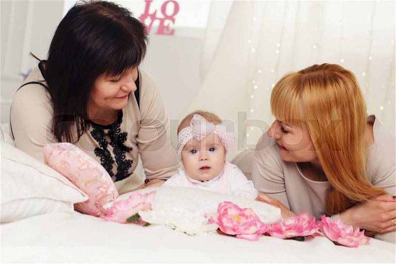 Three steps of family generation: grandmother, mother and granddaughter are lying on bed, stock photo
