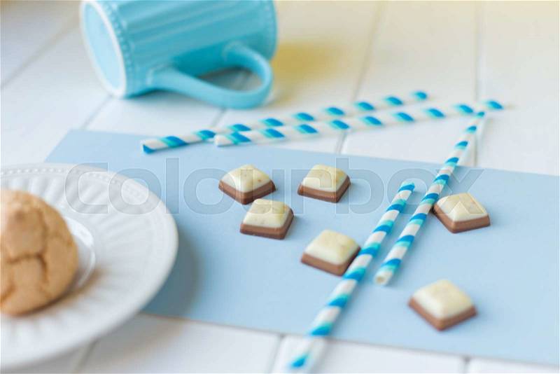 Chocolate candies and coconut cookies on a white wooden background. Still life in white-blue colors, stock photo