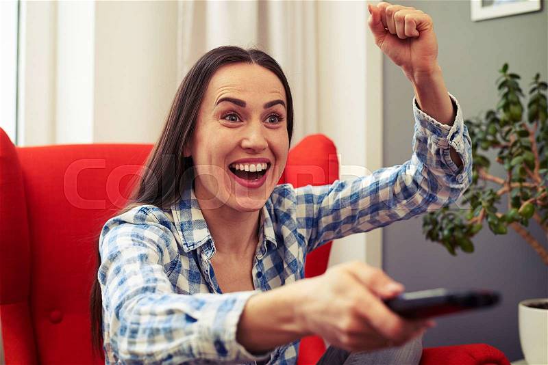 Emotional woman watching football on tv at home, stock photo