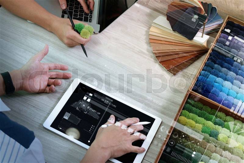 Top view of two colleagues interior designers discussing data with digital tablet and new modern computer laptop with sample material on wooden desk as concept, stock photo