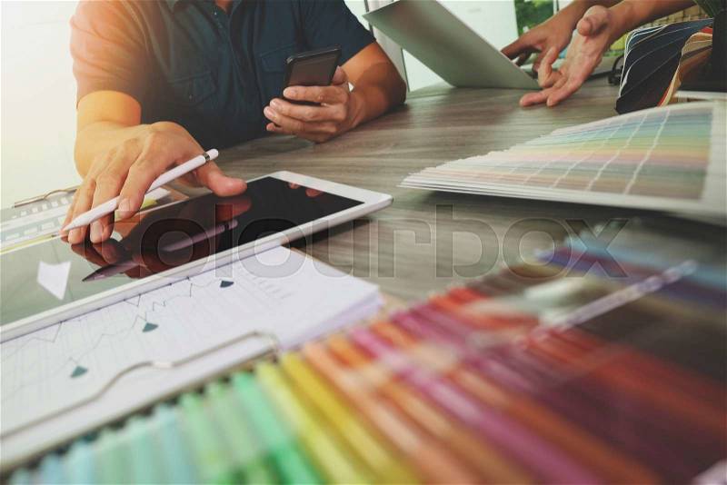 Two colleagues interior designer discussing data and digital tablet and computer laptop with sample material and digital design diagram on wooden desk as concept, stock photo