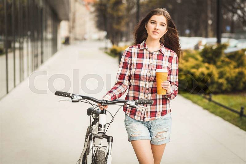 Young beautiful woman with coffee cup and a bicycle, stock photo