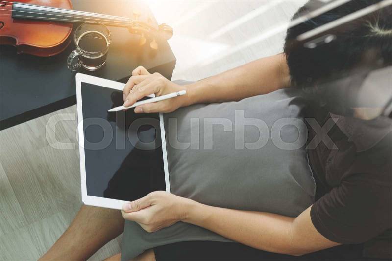 Hipster hand composing music with digital tablet compter and sitting on sofa at home studio, stock photo