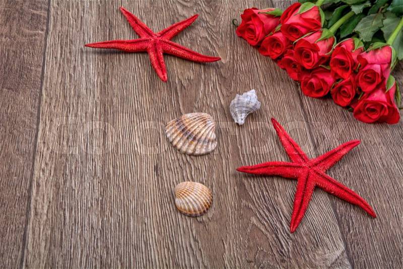 Red starfishes, shells and red roses on a wooden background, stock photo