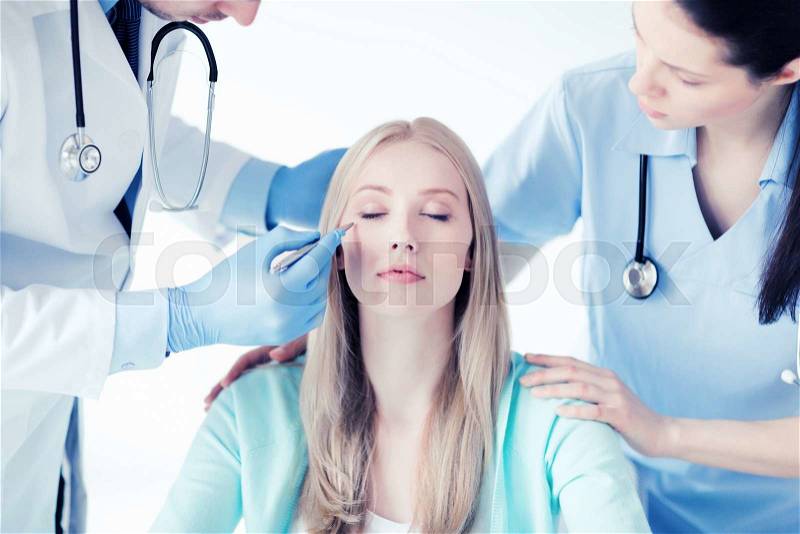 Healthcare, medical and plastic surgery concept - plastic surgeon and nurse with patient in hospital, stock photo
