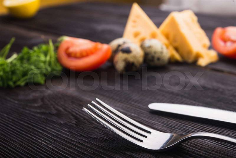 Fork and knife with tomato, cheese, eggs. creative food background, stock photo