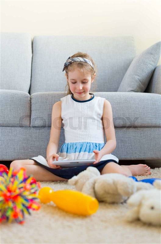It\'s time to clean up your toys! Little girl playing with tablet pc, don\'t want to do the cleaning, stock photo