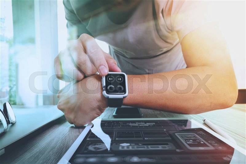Website designer working with smart watch and digital tablet and digital design diagram on wooden desk as concept, stock photo
