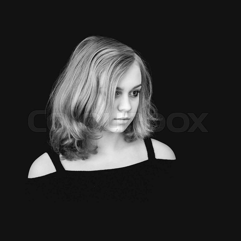 Black and white portrait of beautiful teenage Caucasian blond girl over black background, stock photo