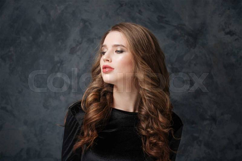 Pretty young woman with long curly hair looking away, stock photo