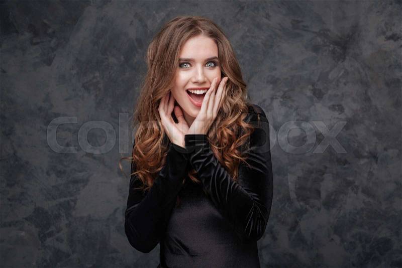 Surprised excited beautiful young woman in black dress, stock photo