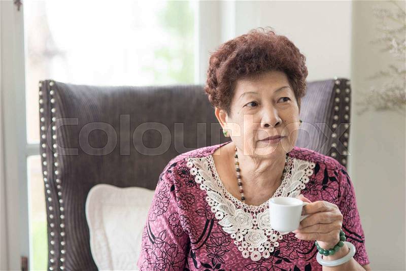 Happy Asian senior woman drinking tea at home. Lifestyle concept, stock photo