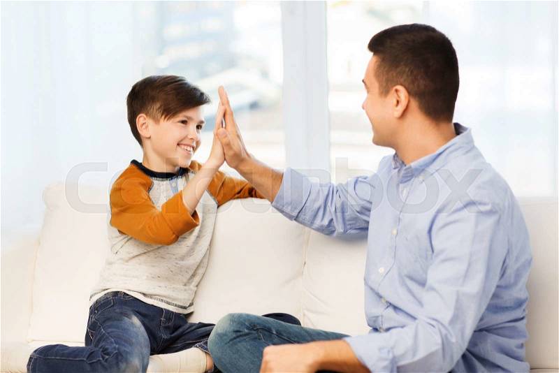 Family, gesture, fatherhood, generation and people concept - happy father and son doing high five at home, stock photo