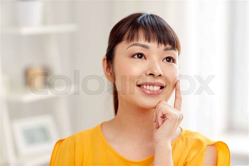 People, race, ethnicity and portrait concept - happy asian young dreaming woman or teenage girl face at home, stock photo