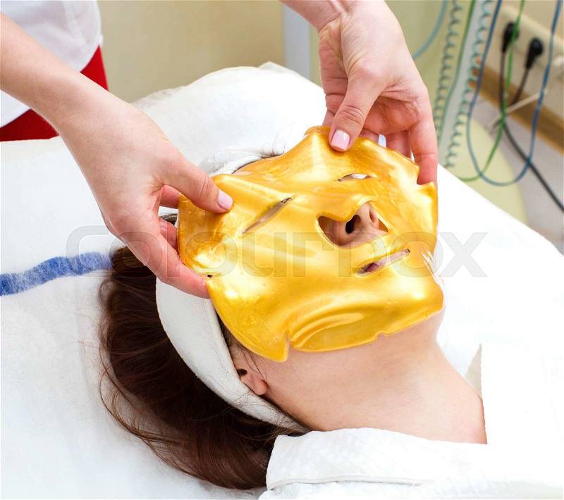 Gold mask cosmetic procedure in the beauty salon, stock photo