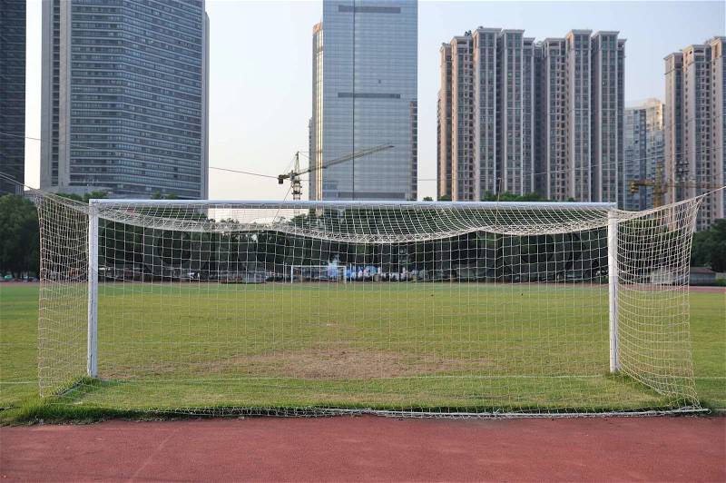Football goal with football field and buildings as background, stock photo