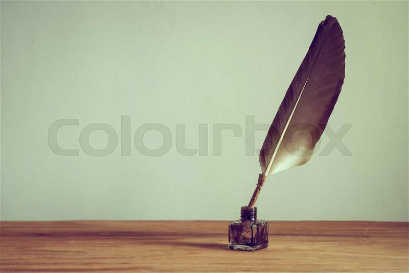 Vintage old quill pen, inkwell on wooden table. Vintage style filtered photo, stock photo