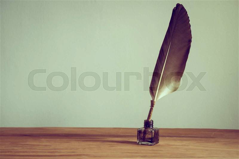Vintage old quill pen, inkwell on wooden table. Vintage style filtered photo, stock photo