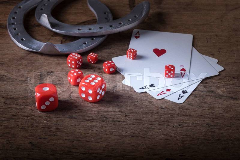 Lucky craps game dice rolling out chance number nine and vintage poker cards with winning aces by old horseshoes for player and gambler good luck charm on rustic wood table in western gambling saloon, stock photo