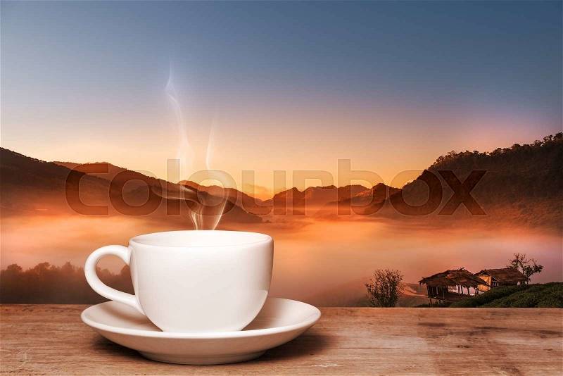 Morning cup of coffee with tea tree in mountain background at sunrise, stock photo