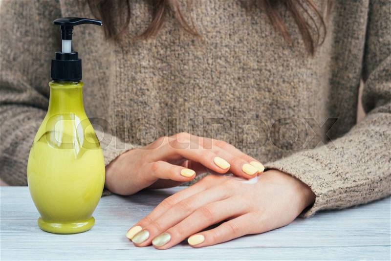 Women\'s hands with yellow manicure applied the cream for hands, stock photo