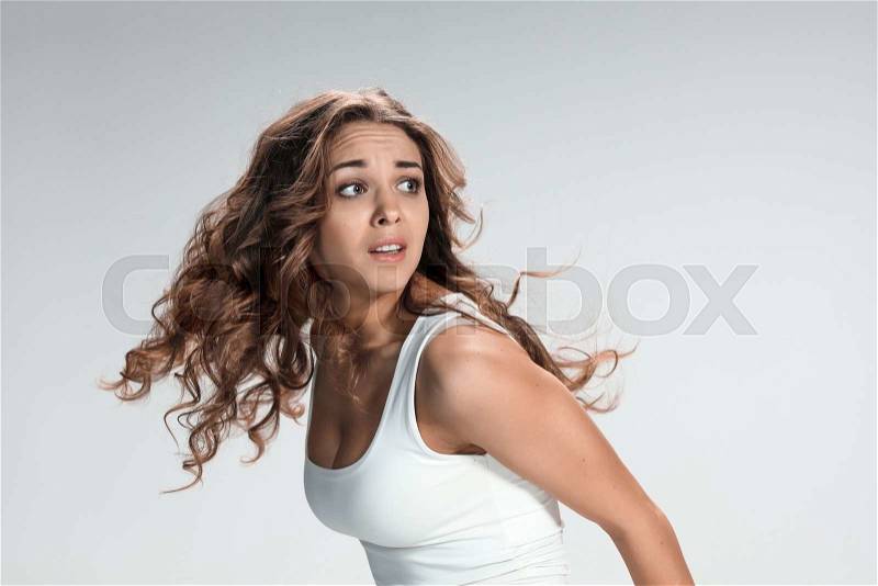 The young woman\'s portrait with frightened emotions on gray background, stock photo