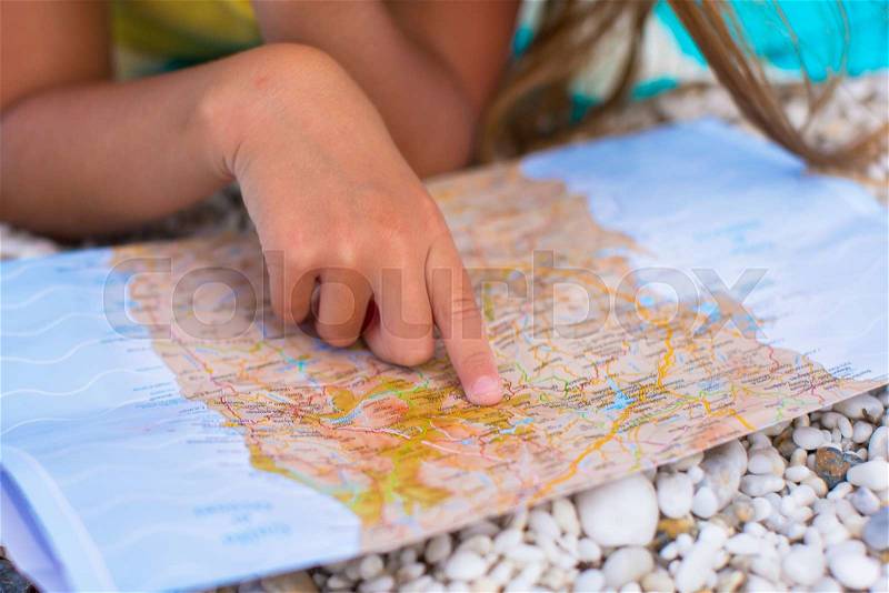 Little cute girl with big map on tropical beach, stock photo