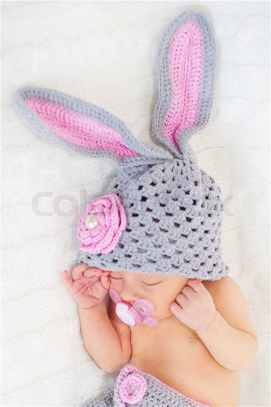 Sleeping newborn baby in rabbit costume on a knitted blanket, stock photo