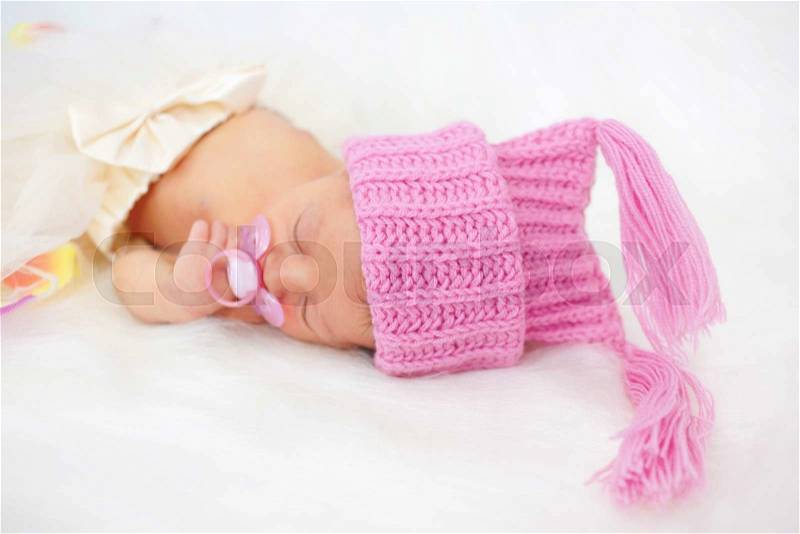 Pretty newborn girl sleeping. Baby dressed in a knitted cap, stock photo