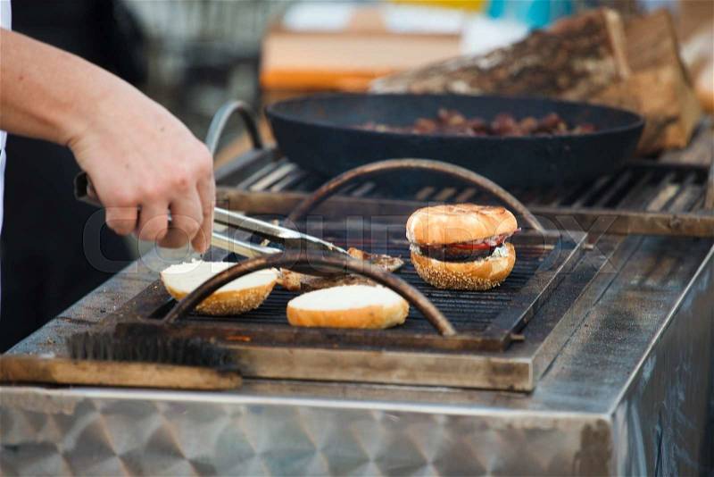 The beef burger with bun on the hot grill. Good snack for outdoors party or picnic, stock photo