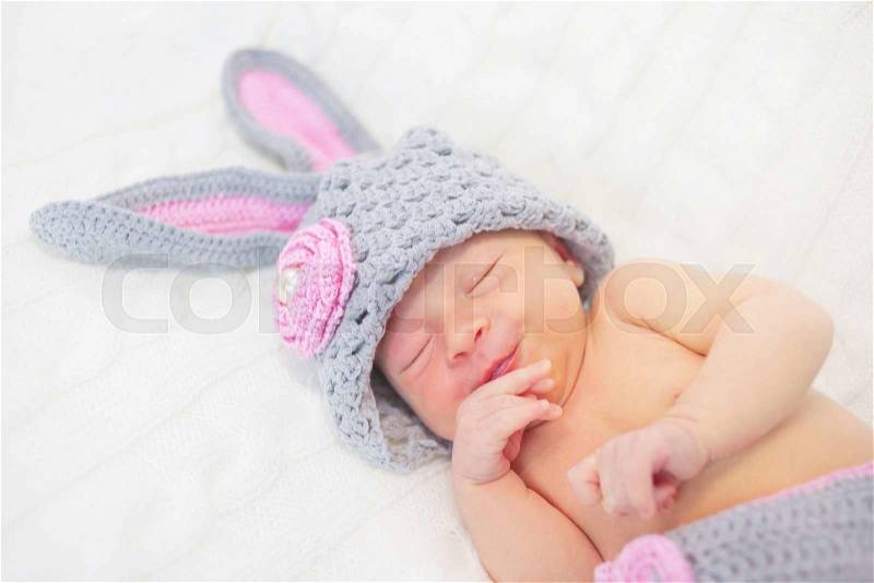 Sleeping smiling newborn baby in rabbit costume, stock photo