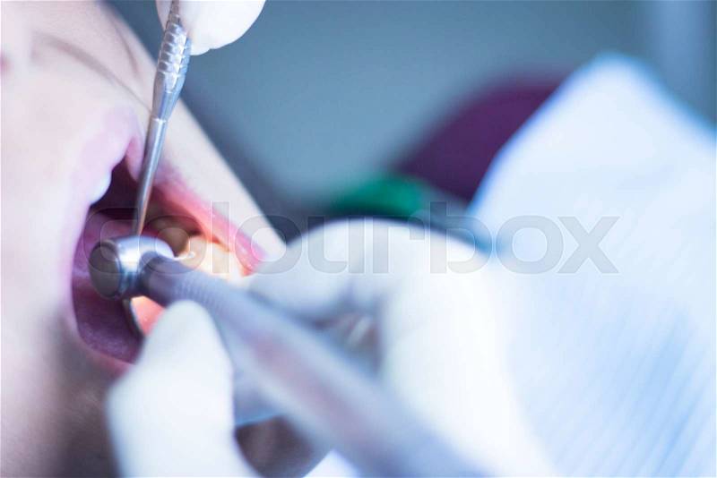 Dentist examining patient mouth in dental exam with dentist\'s drill instrumentation in clinic, stock photo