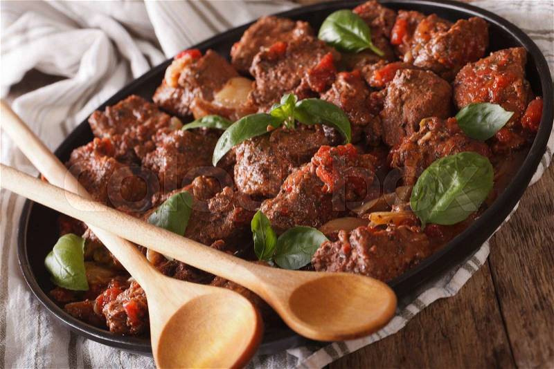 Spicy beef with sauce and basil close up in a dish on the table. horizontal , stock photo