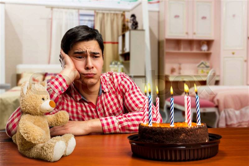 Sad birthday boy and cake with candle at the table , stock photo