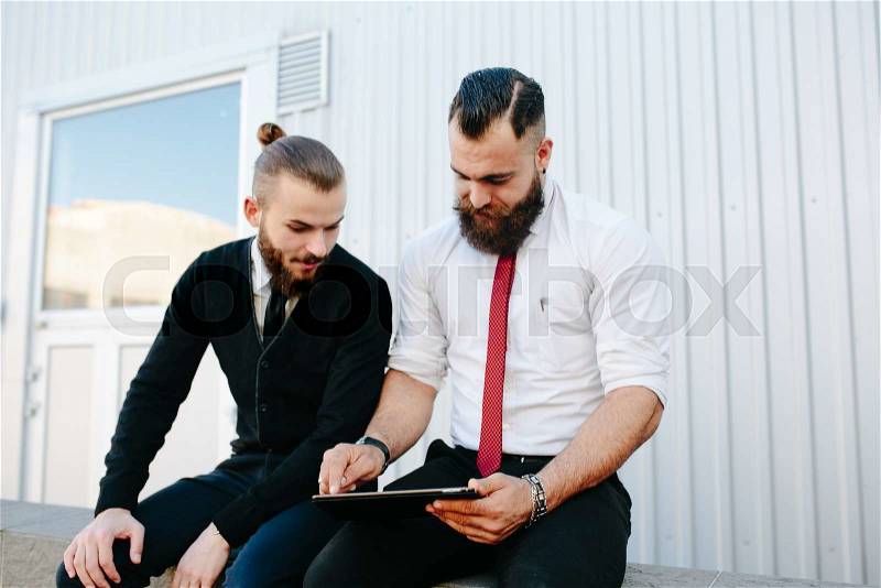 Two businessmen discussing something and looking at pad, stock photo