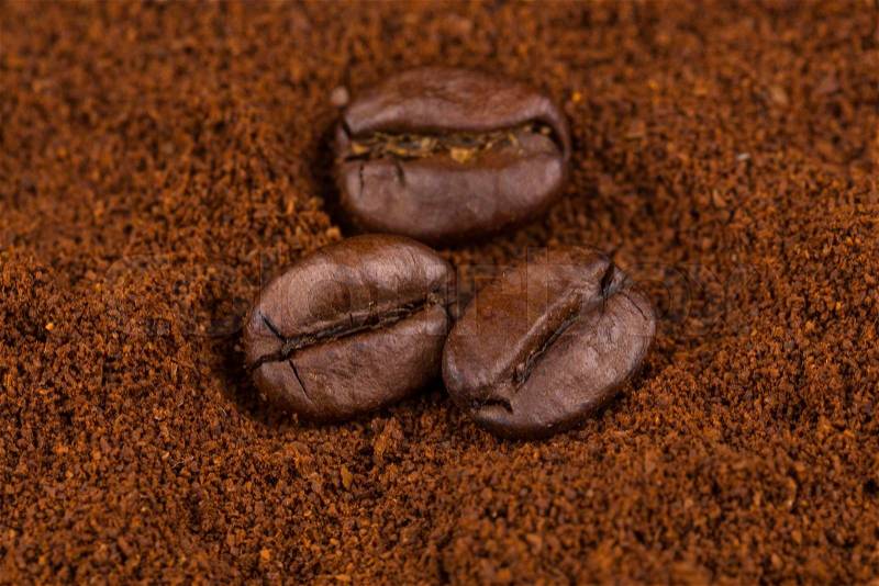 Coffee beans on heap of ground coffee close-up, stock photo