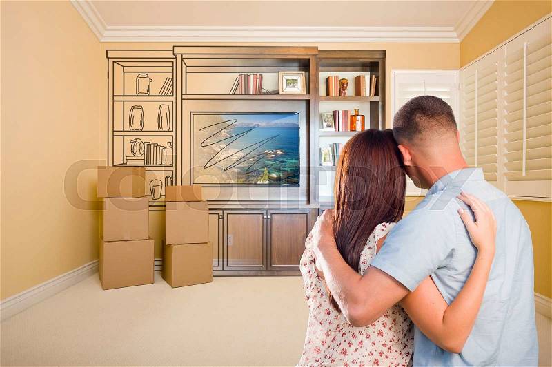 Young Military Couple Looking At Drawing of Entertainment Unit In Room With Moving Boxes, stock photo