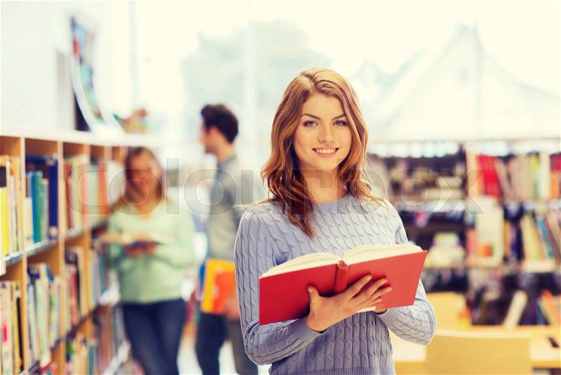People, knowledge, education and school concept - happy student girl or young woman with book in library, stock photo