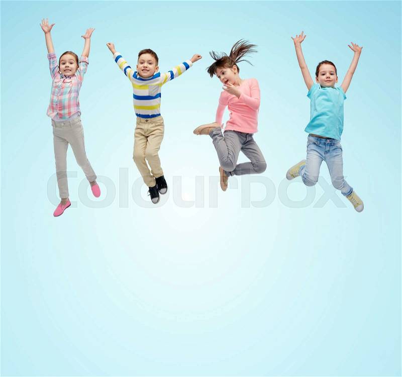 Happiness, childhood, freedom, movement and people concept - happy little children jumping in air over blue background, stock photo