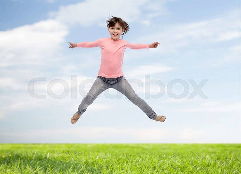 Happiness, childhood, freedom, movement and people concept - happy little girl jumping in air over blue sky and grass background, stock photo