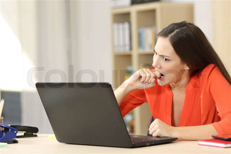 Angry entrepreneur furious with a laptop working in an office or home, stock photo