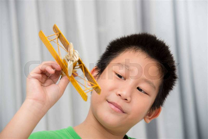 Asian boy playing yellow vintage plane at home, stock photo