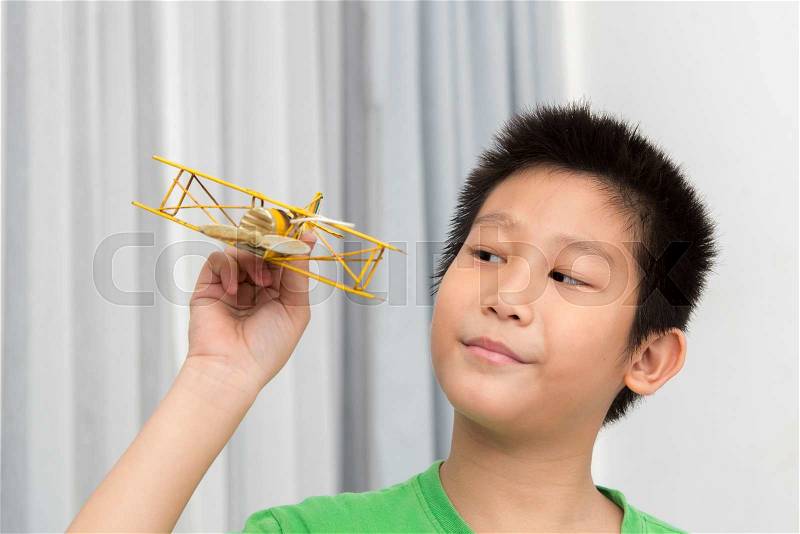Asian boy playing yellow vintage plane at home, stock photo