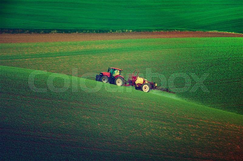 Farm machinery spraying insecticide to the green field, agricultural natural seasonal spring background, vintag retro hipster style, stock photo