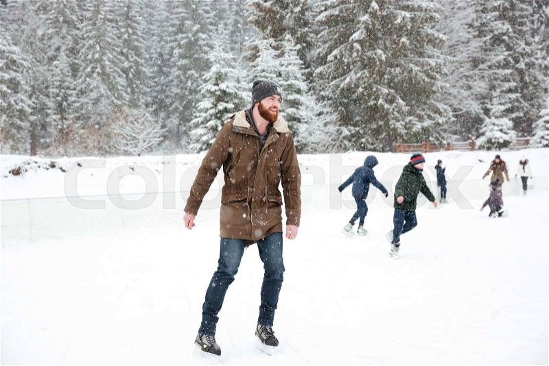 Portrait of a happy man ice skating outdoors, stock photo