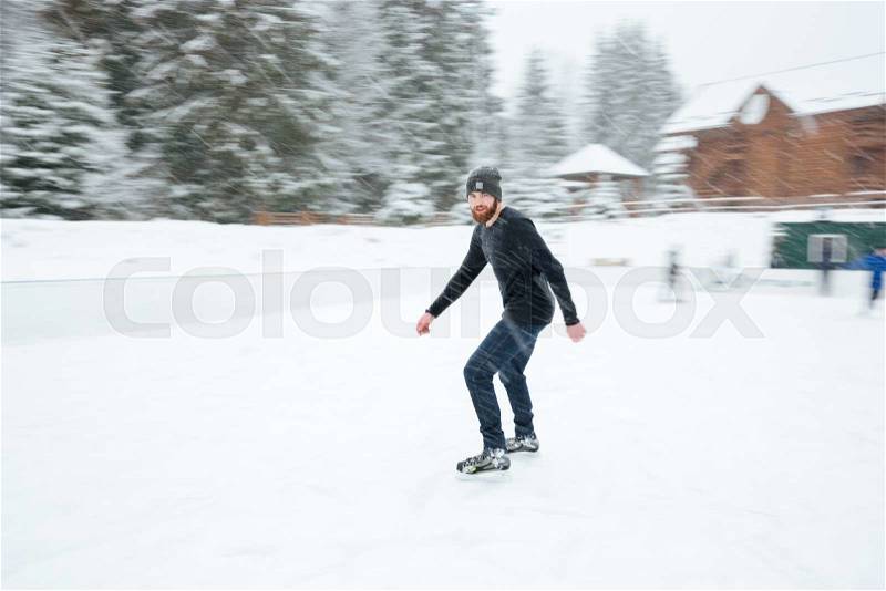 Man ice skating outdoors with snow on background, stock photo