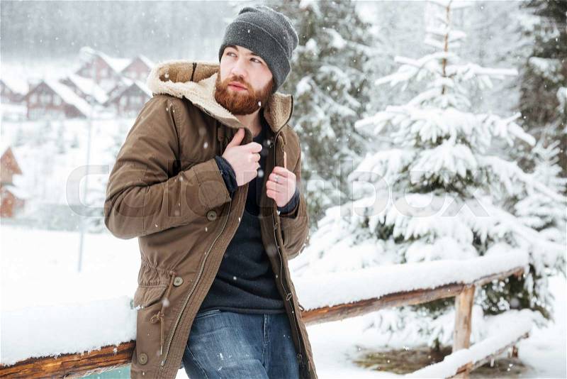 Attractive bearded man standing outdoors in wwnter, stock photo