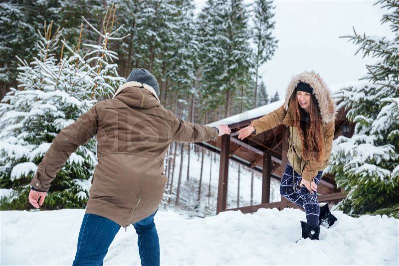 Beautiful couple reaching hands and helping each other while walking in mountains in winter, stock photo